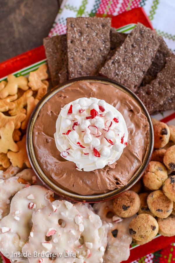 Overhead picture of a bowl of chocolate cheesecake dip surrounded by cookies and pretzels.