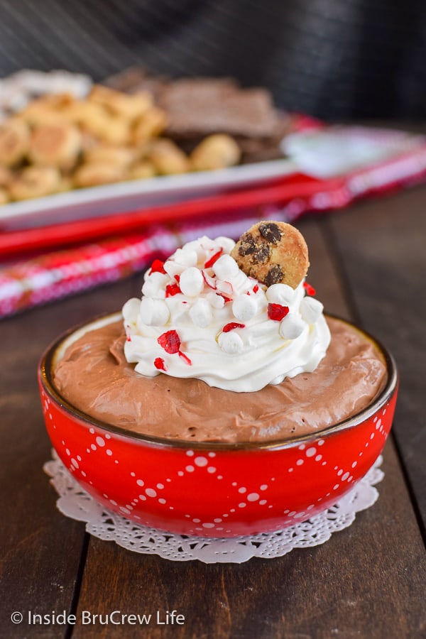 A red bowl filled with hot chocolate cheesecake dip and topped with whipped cream.