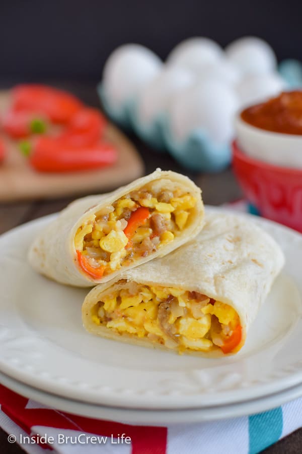 Two halves of an egg burrito stacked on a white plate.