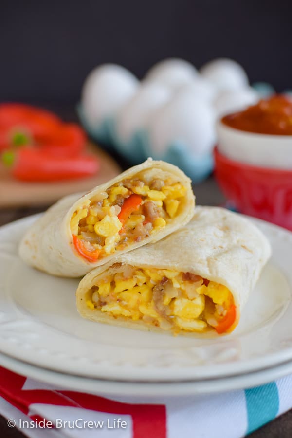 Two halves of an egg burrito stacked on a white plate.