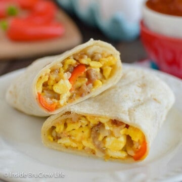 Two halves of an egg burrito stacked on a white plate.