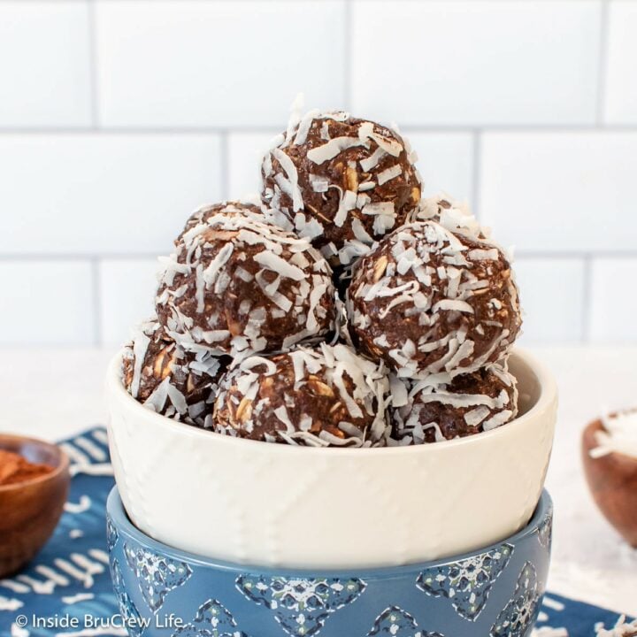 A bowl of almond joy energy bites on a white board.