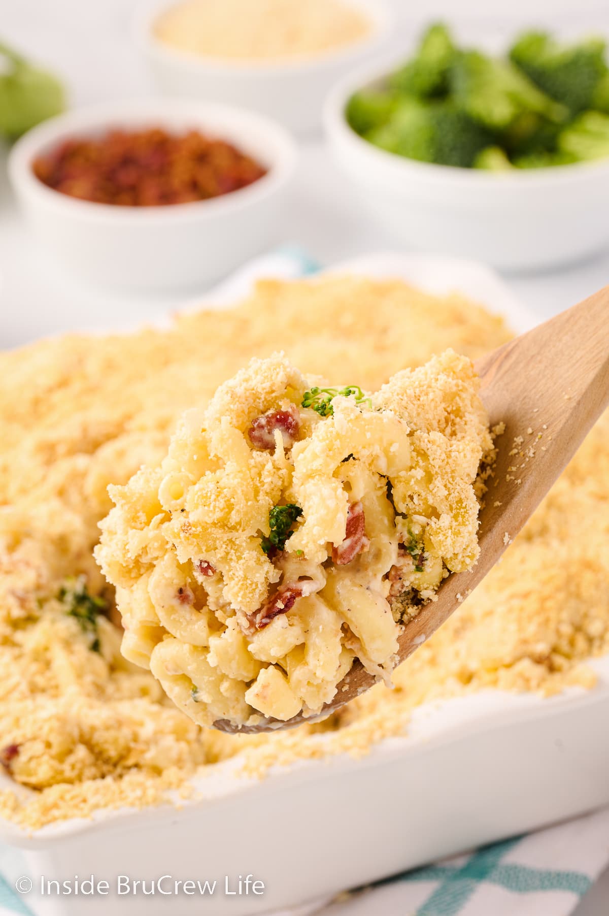 A scoop of baked macaroni and cheese being lifted out of a pan.