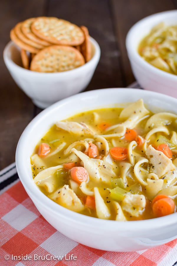 A close up of a white bowl filled with chicken soup.