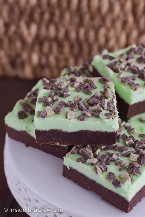 A white cake plate with chocolate mint sugar cookie bars stacked on it