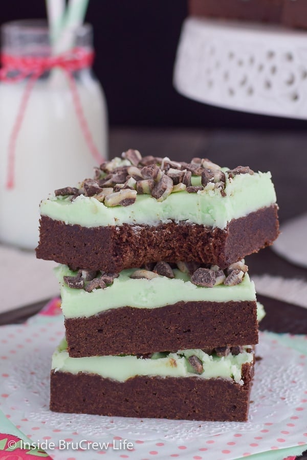 A stack of chocolate mint sugar cookie bars topped with Andes mints on a white doily