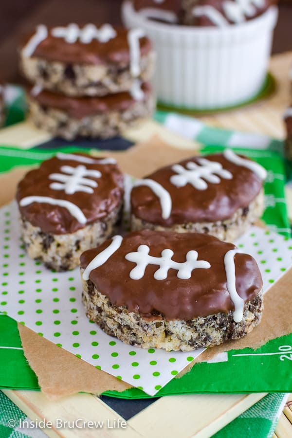 Three football rice krispie treats on a green and white paper.