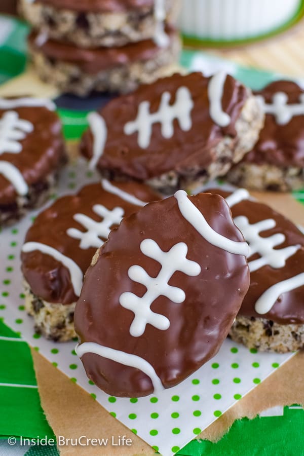 Football shaped rice krispie treats stacked on a white and green paper.