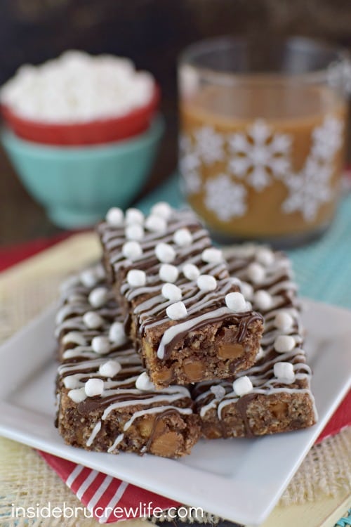 A white plate with three salted caramel hot chocolate granola bars on it and coffee behind it