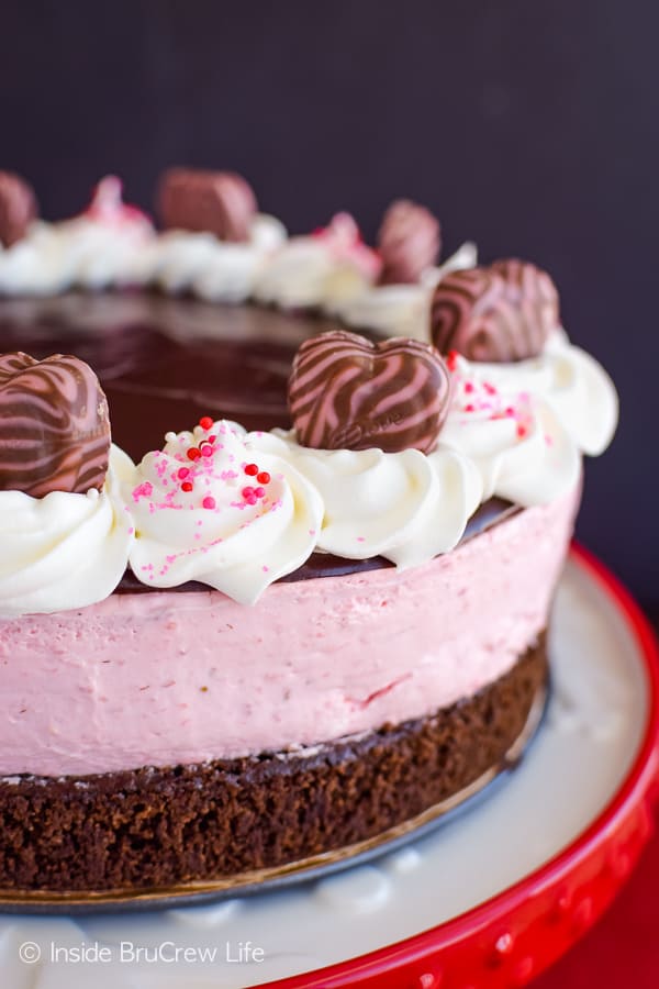 A white and red cake plate with a chocolate and strawberry dessert on it.