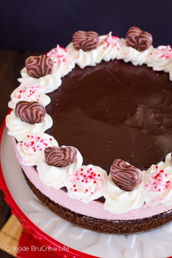 A chocolate covered strawberry mousse on a red and white cake plate.