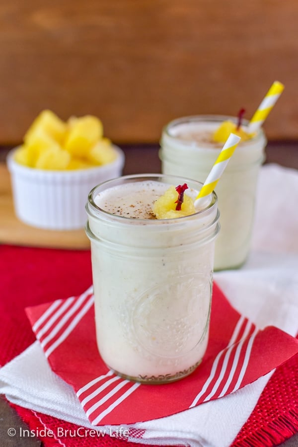 Two clear glasses filled with vanilla pineapple smoothie on a red napkin