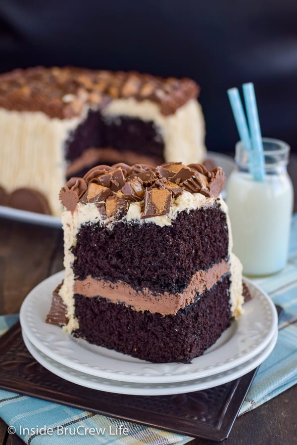 Best Chocolate Peanut Butter Cake - This homemade chocolate cake is covered in peanut butter frosting and peanut butter cups. Make this recipe to see why this is the best chocolate cake ever! A white plate with a slice of best chocolate cake topped with peanut butter frosting and peanut butter cups.
