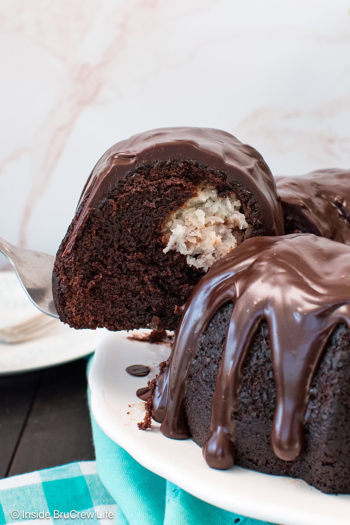 A chocolate bundt cake slice being lifted out of a cake.