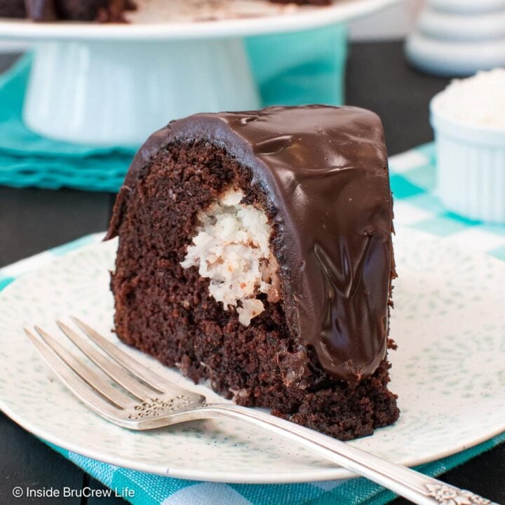 A slice of chocolate cake with glaze on a white plate.