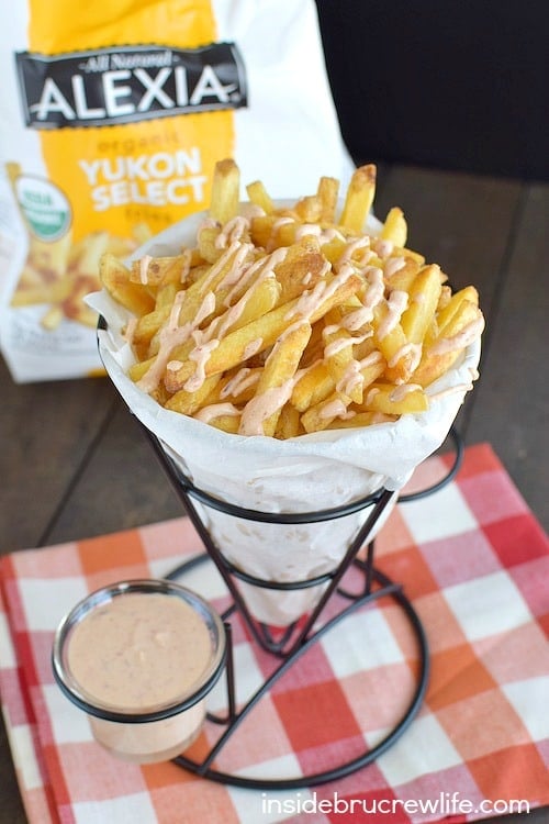 A paper cone full of fries and dipping sauce.