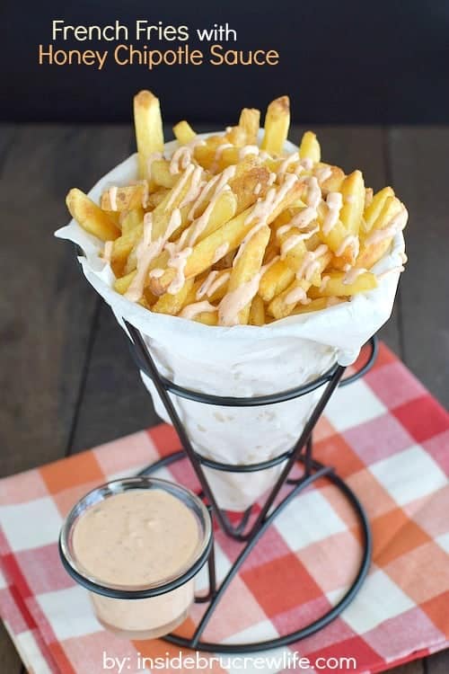 A paper cone full of fries and dipping sauce.