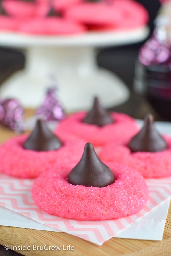 Four pink cookies with Hershey kisses on a wooden board.
