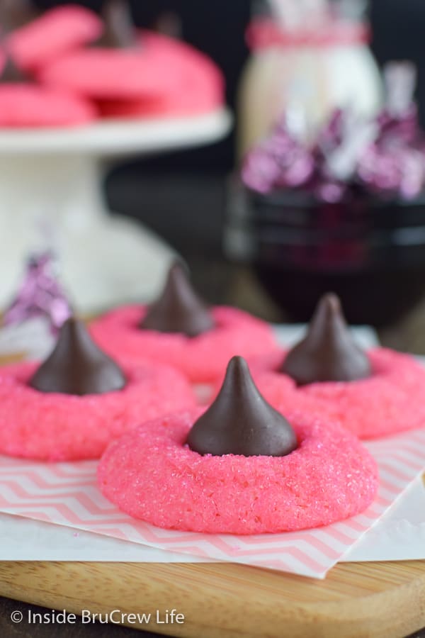 Pink strawberry cookies topped with kisses on a cutting board.