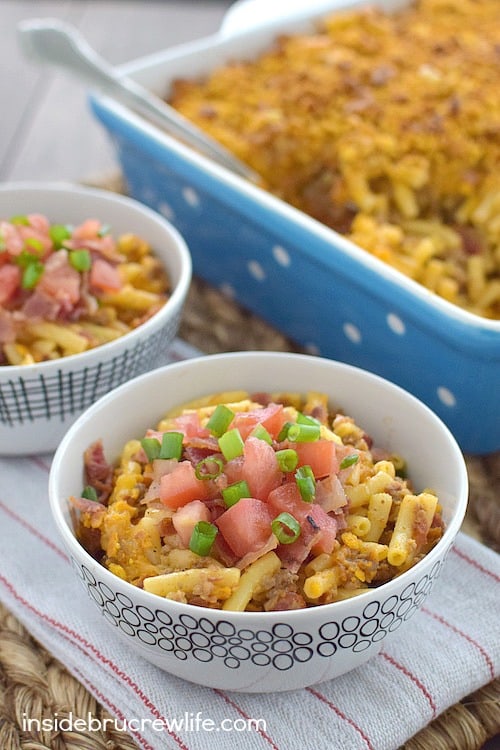 Two bowls filled with cheesy bacon casserole and topped with bacon and tomatoes.