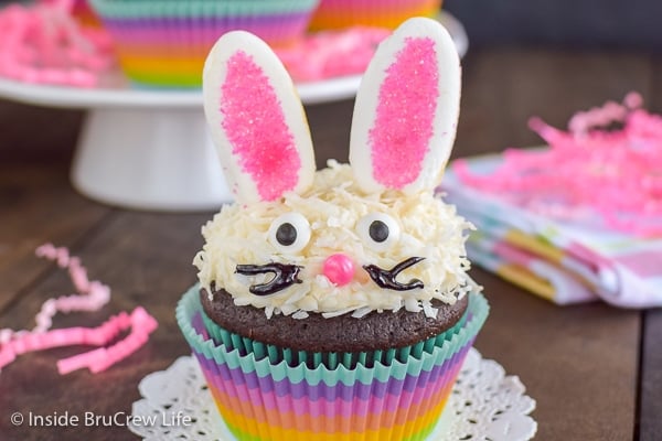 A coconut topped cupcake decorated with marshmallow ears and a candy face to look like an Easter bunny