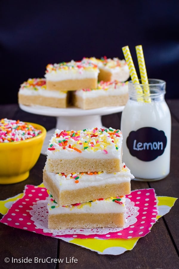 Three lemon cookie bars with frosting stacked on top of each other.