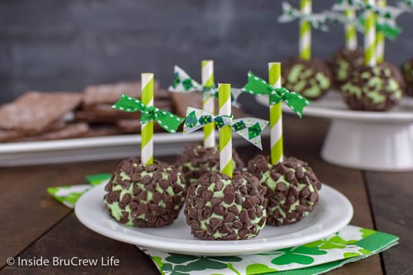 4 green mint cream cheese balls covered in mini chocolate chips on a white plate.