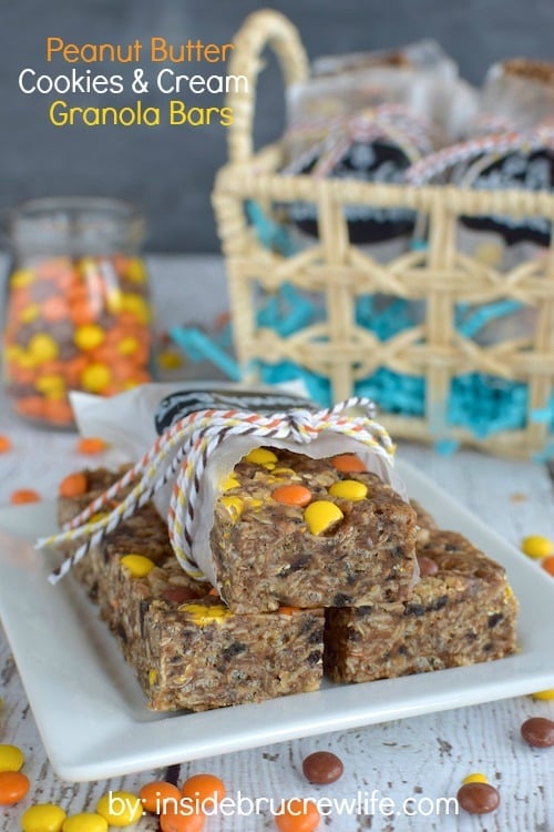 A white plate with peanut butter cookies and cream granola bars on it and jar of Reese's candies behind it