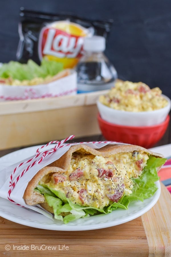 A pita pocket filled with egg salad on a white plate.