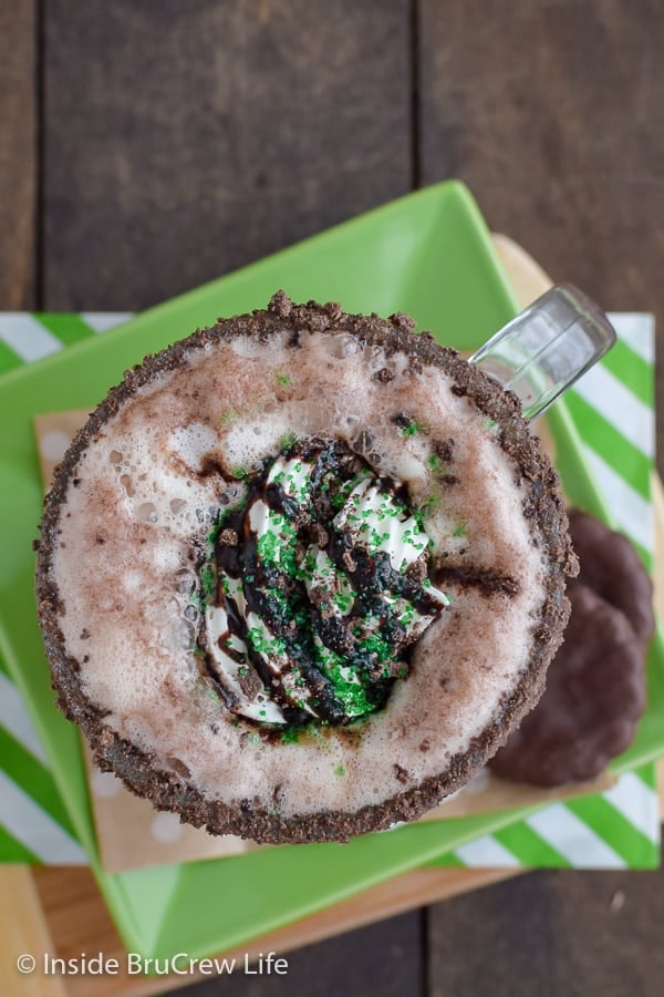 An overhead picture of a chocolate mint latte with cream and green sprinkles on top.