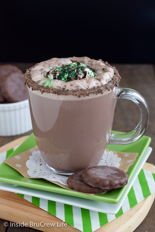 A clear mug full of a chocolate mint latte on a green plate.