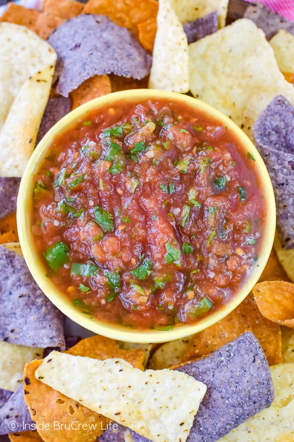 Close up of a yellow bowl filled with homemade salsa and surrounded by tortillas chips