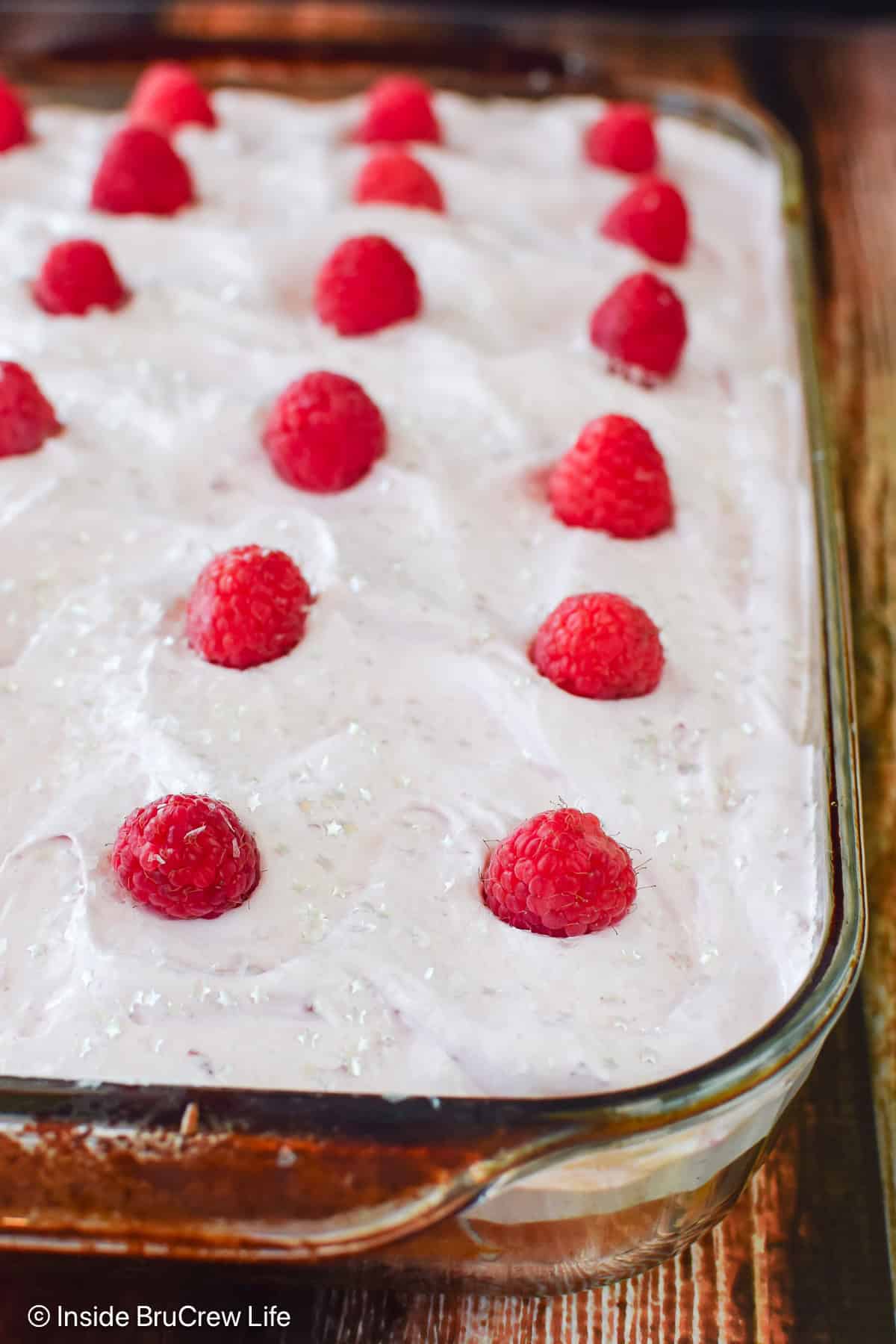 A frosted raspberry poke cake in a glass pan.