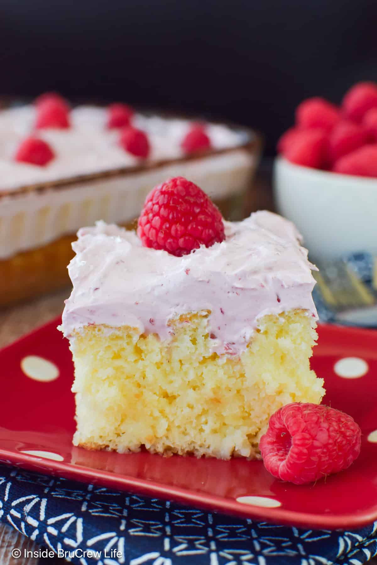 A slice of hazelnut raspberry poke cake on a red polkadot plate.
