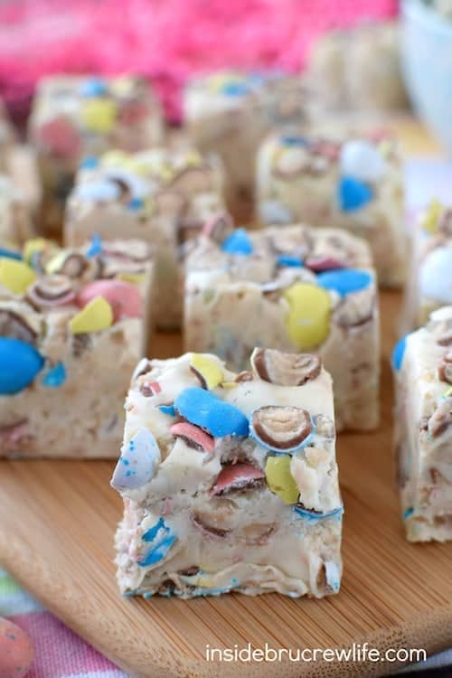 Vanilla fudge loaded with malt robin eggs on a wooden cutting board.