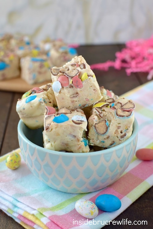 Vanilla fudge loaded with malt robin eggs in a blue and white bowl on a colorful towel.