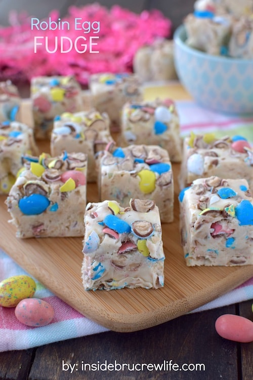 Vanilla fudge loaded with malt robin eggs on a wooden cutting board.