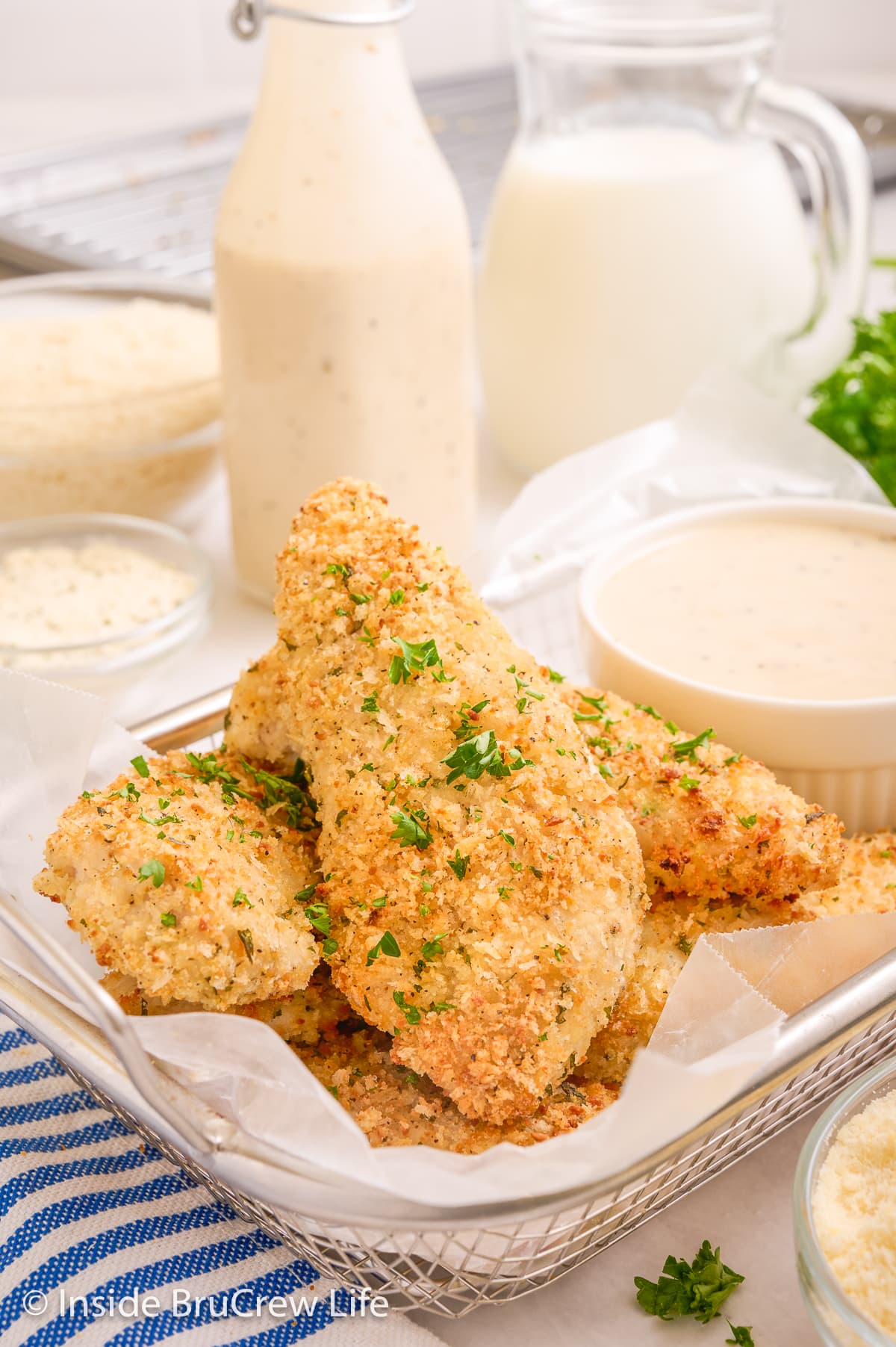 Baked chicken tenders in a wire basket with a cup of ranch.