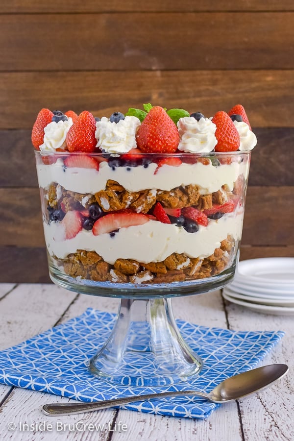 A large clear trifle dish filled with a berry trifle made up of layers of oatmeal cream pies, no bake cheesecake, and fresh fruit