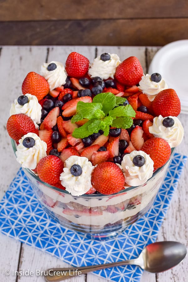 Picture of the top of a berry trifle decorated with strawberries, blueberries, Cool Whip, and mint leaves