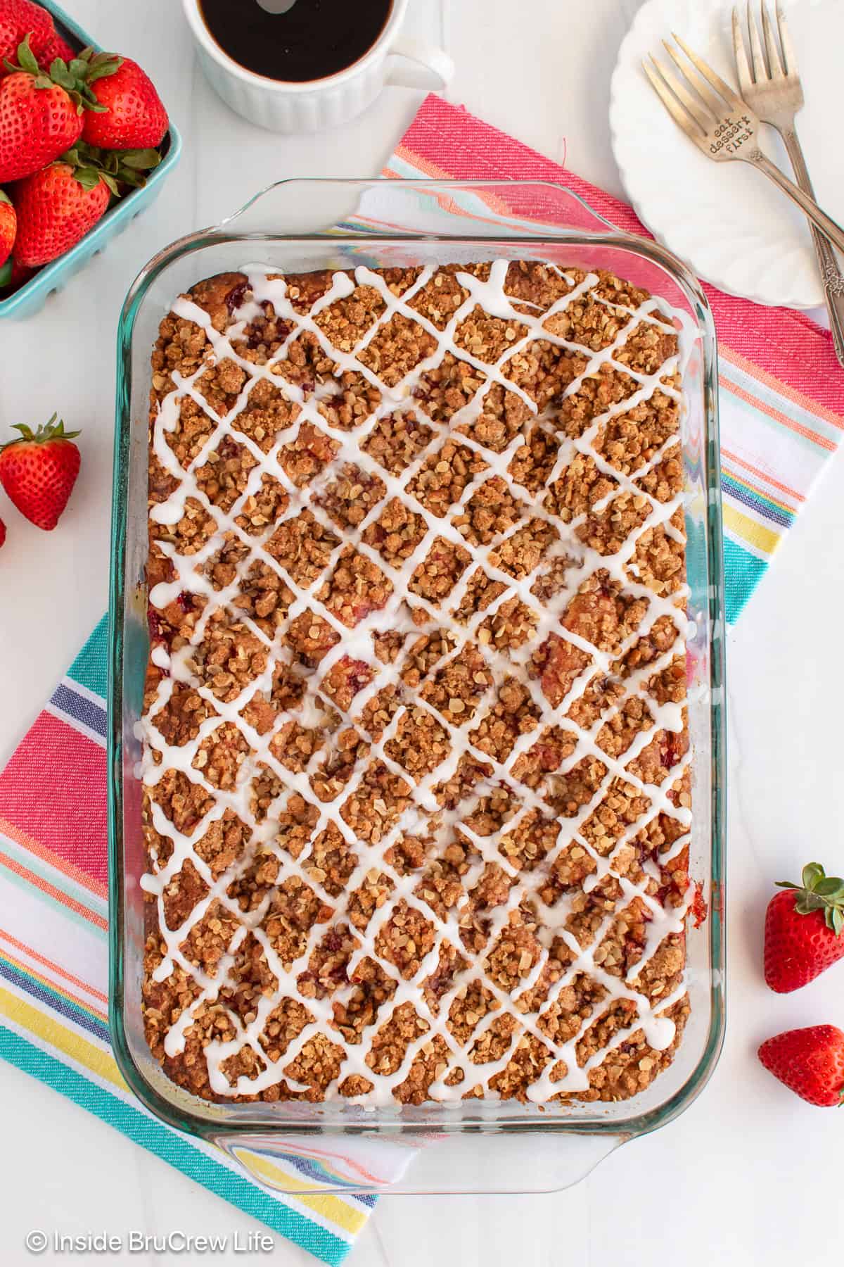 An overhead picture of a strawberry banana cake with crumble and glaze toppings.
