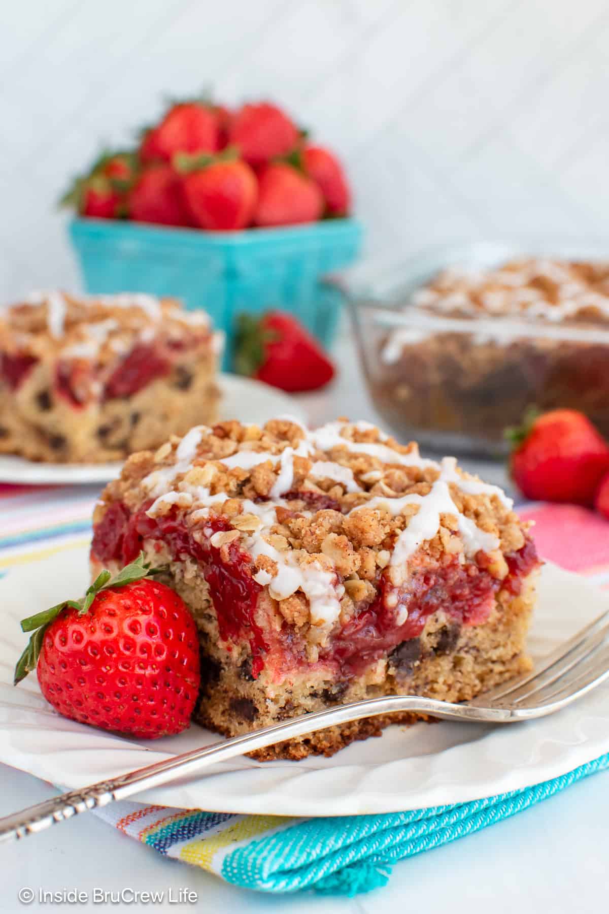 Two white plates with squares of strawberry banana cake on it.