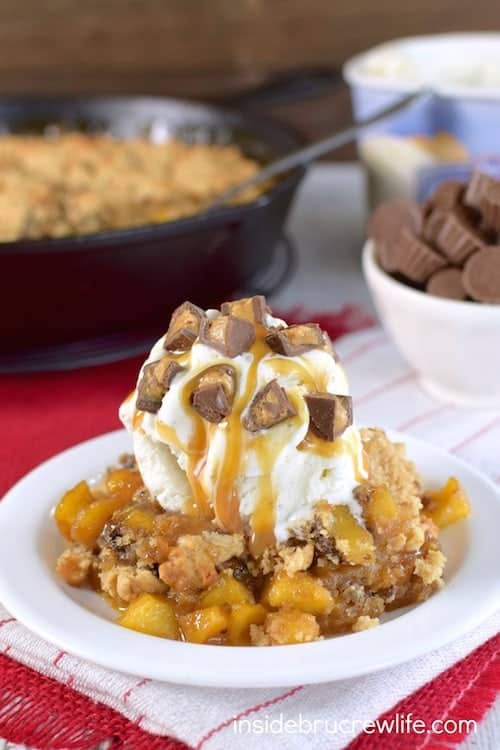 A bowl of apple crisp topped with ice cream and chocolate candies.