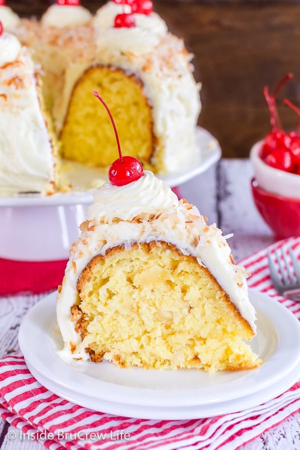 A white plate on a red and white towel with a slice of pina colada bundt cake on it