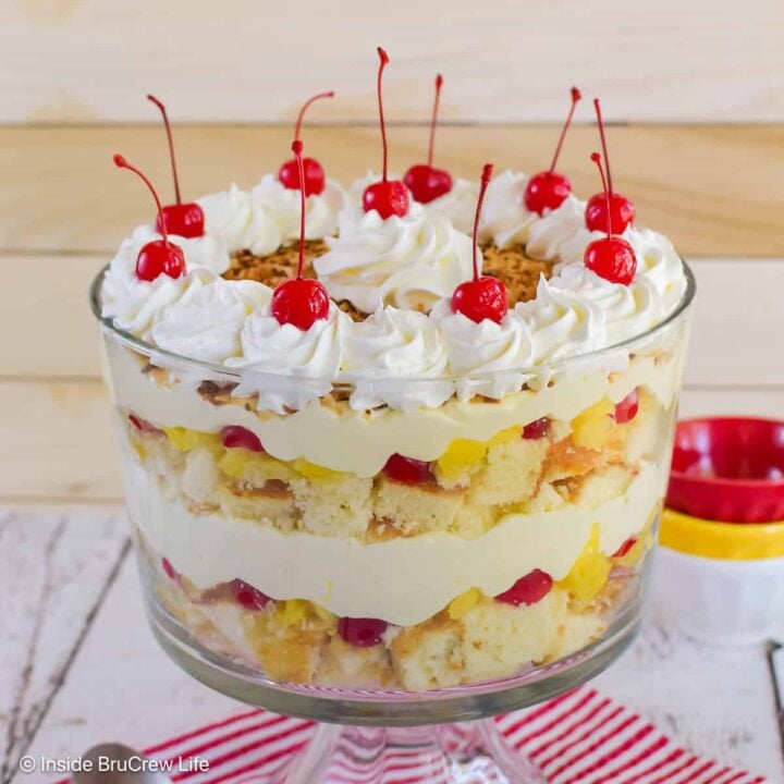 A large clear bowl filled with a pina colada trifle and topped with cherries.