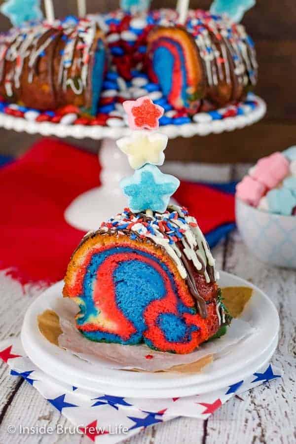 A slice of red white and blue bundt cake on a white plate with a marshmallow skewer on top