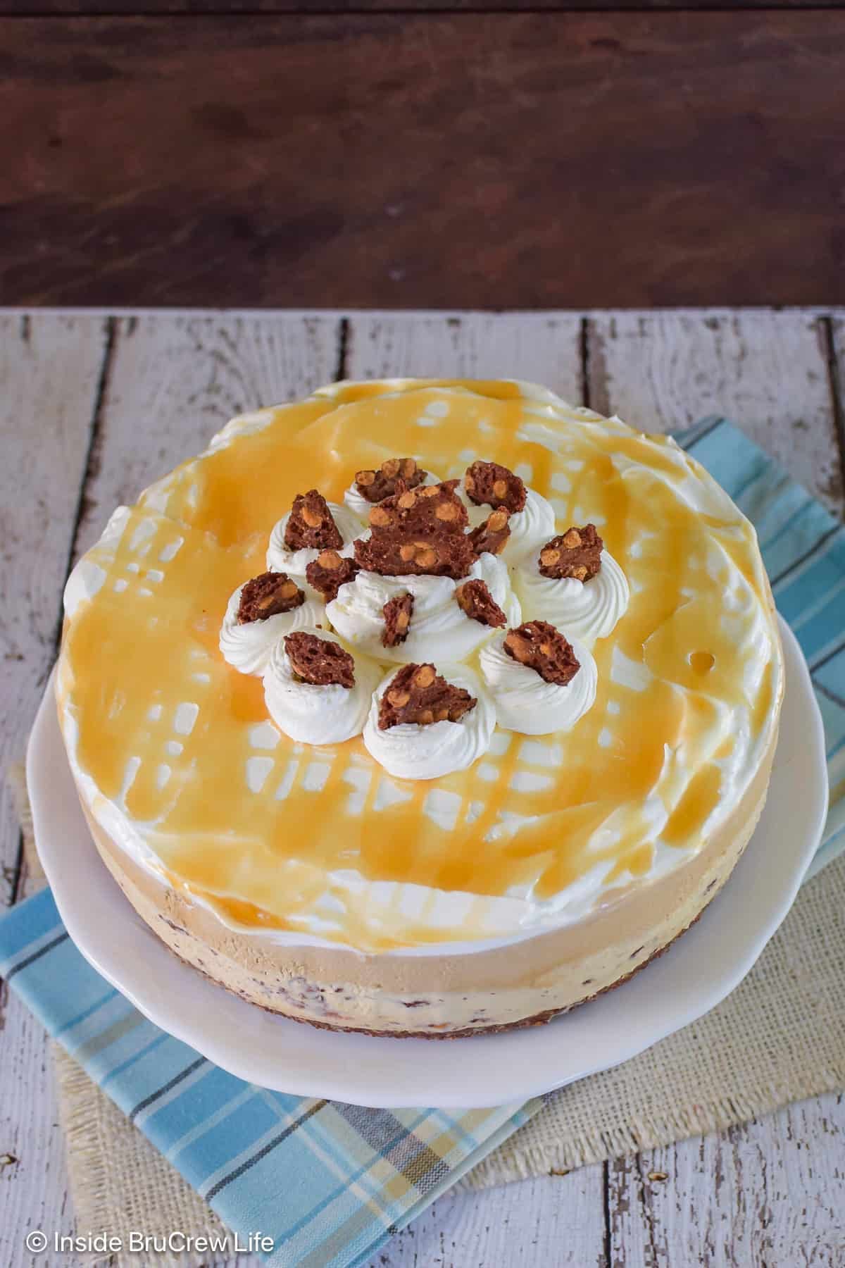 Caramel drizzles and Cool Whip on top of a round ice cream cake.