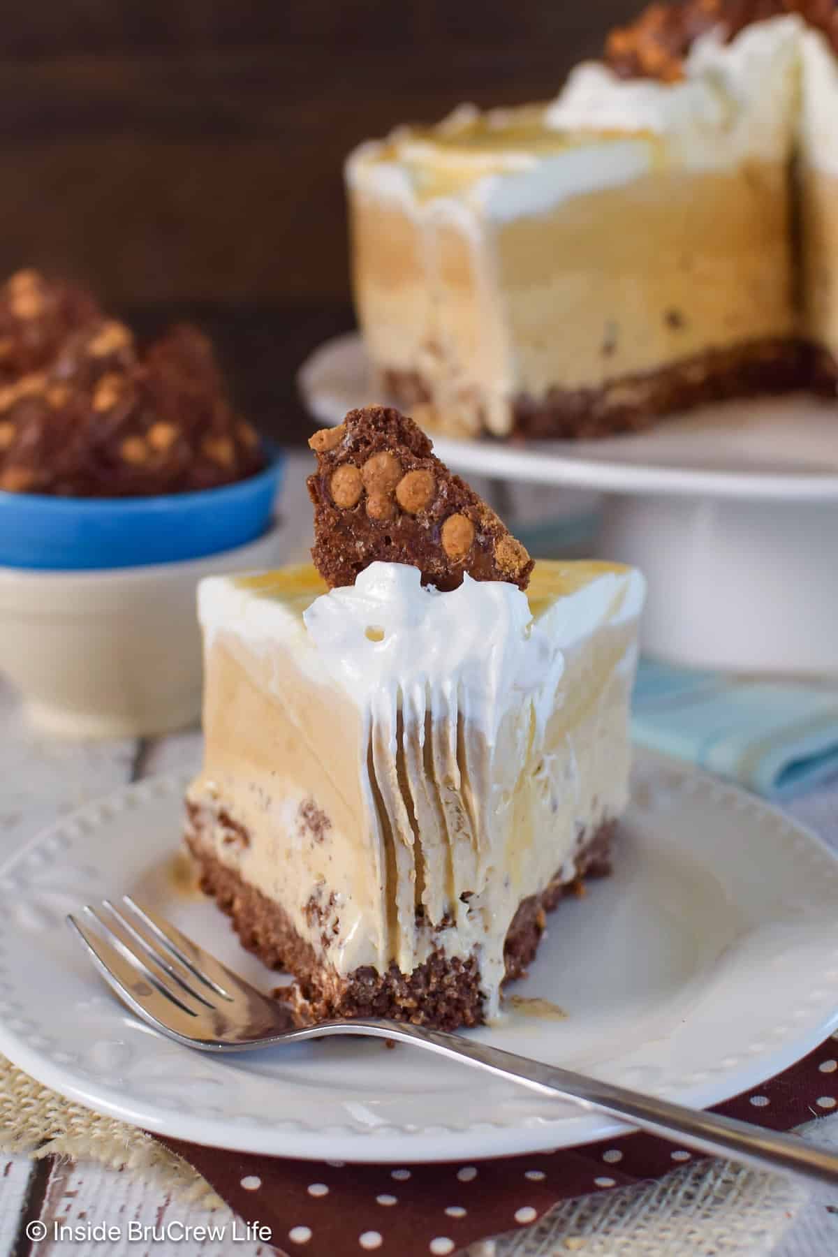 A slice of coffee caramel ice cream cake on a plate with a bite take out of it.