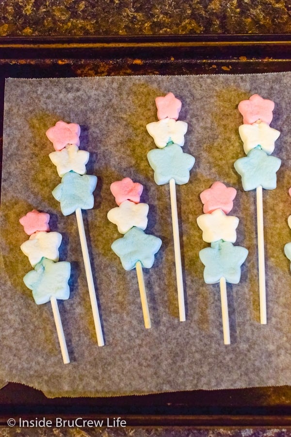 Star marshmallow pops on a metal sheet pan