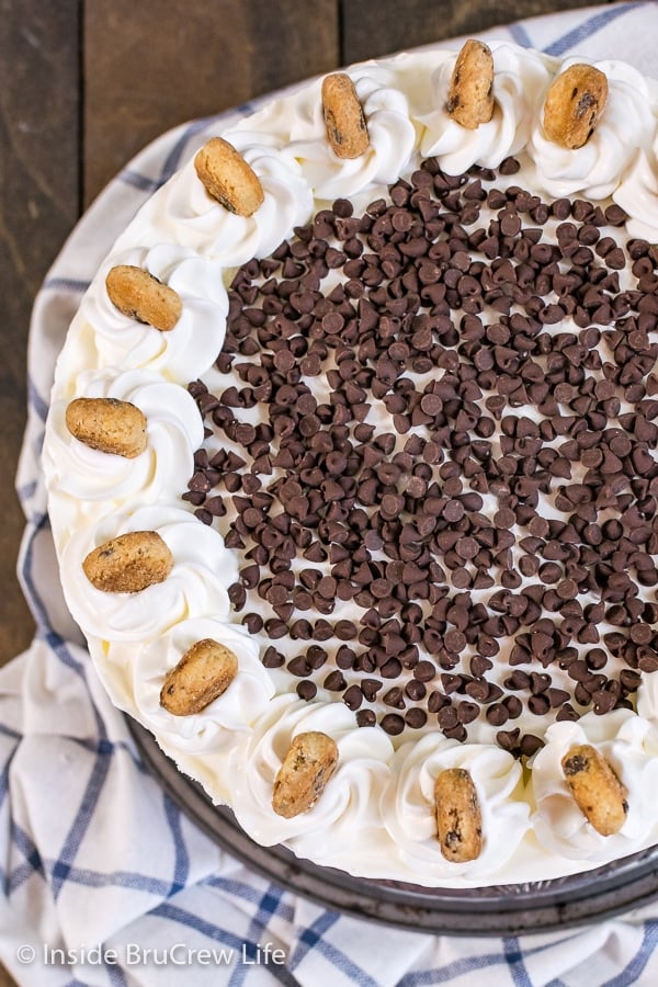 A picture of the top of a chocolate chip cookie dough ice cream cake with chocolate chips and mini cookies on top